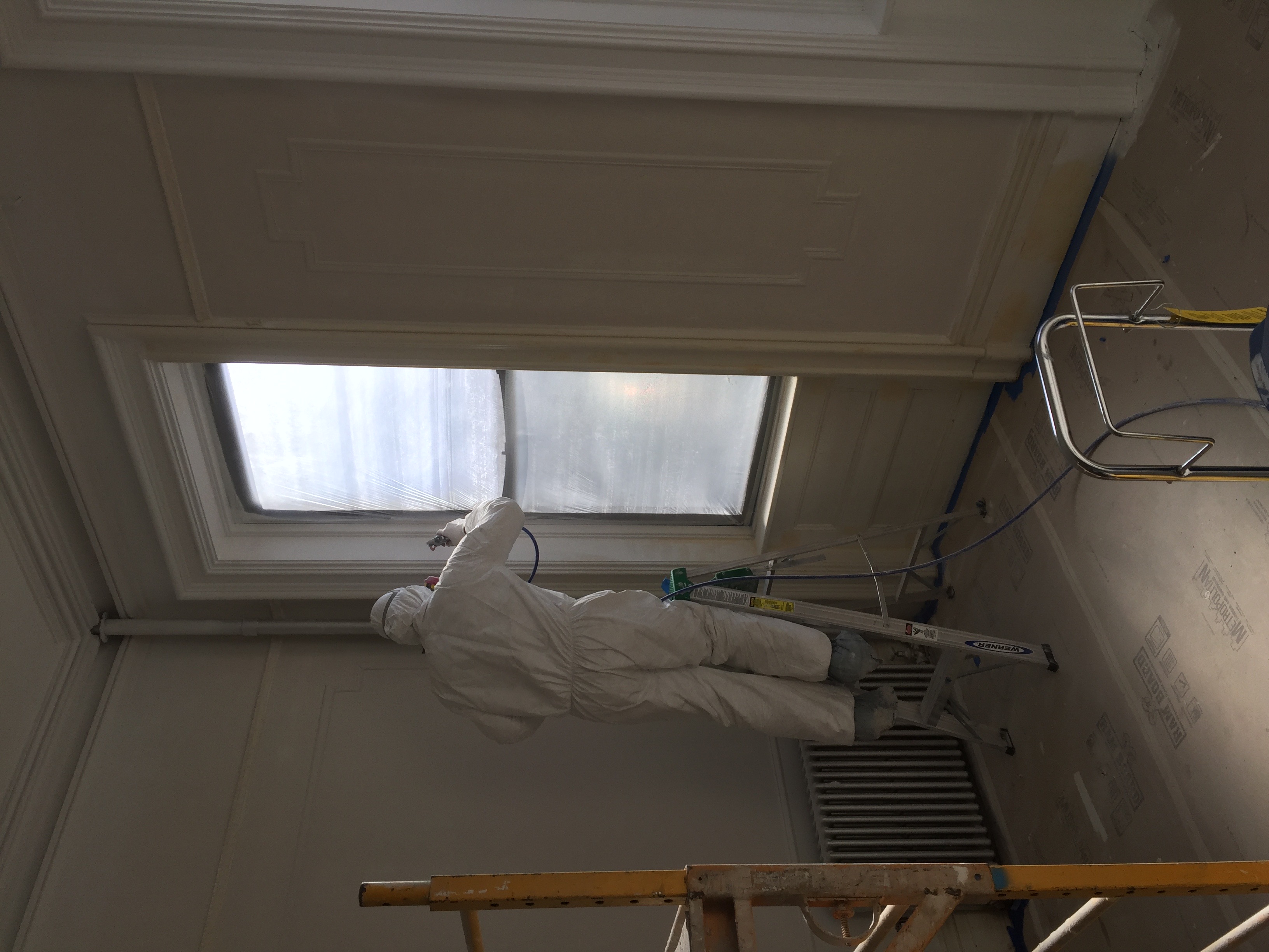 Painter spraying window trim